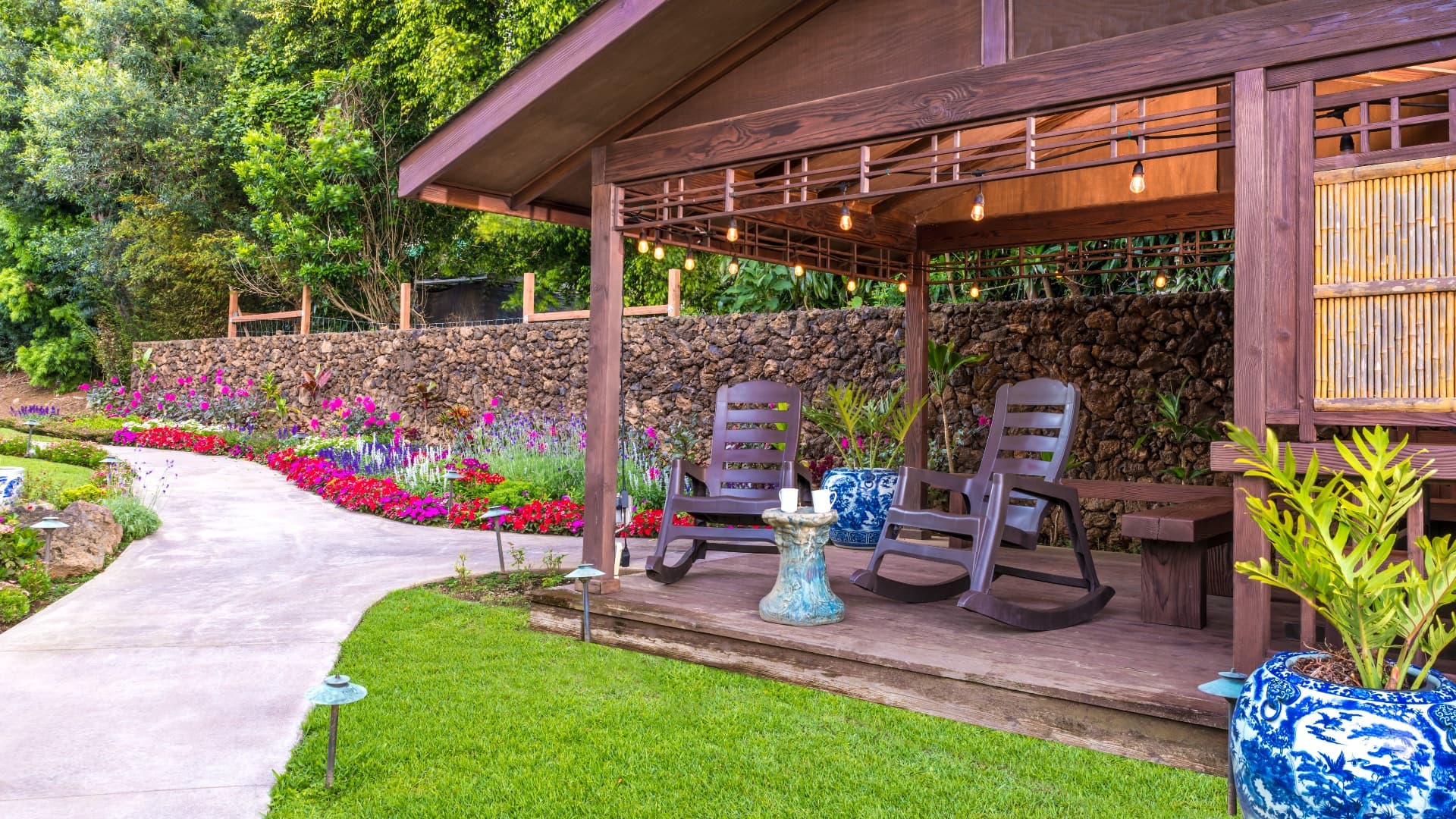 A serene outdoor seating area with rocking chairs and vibrant flower beds.